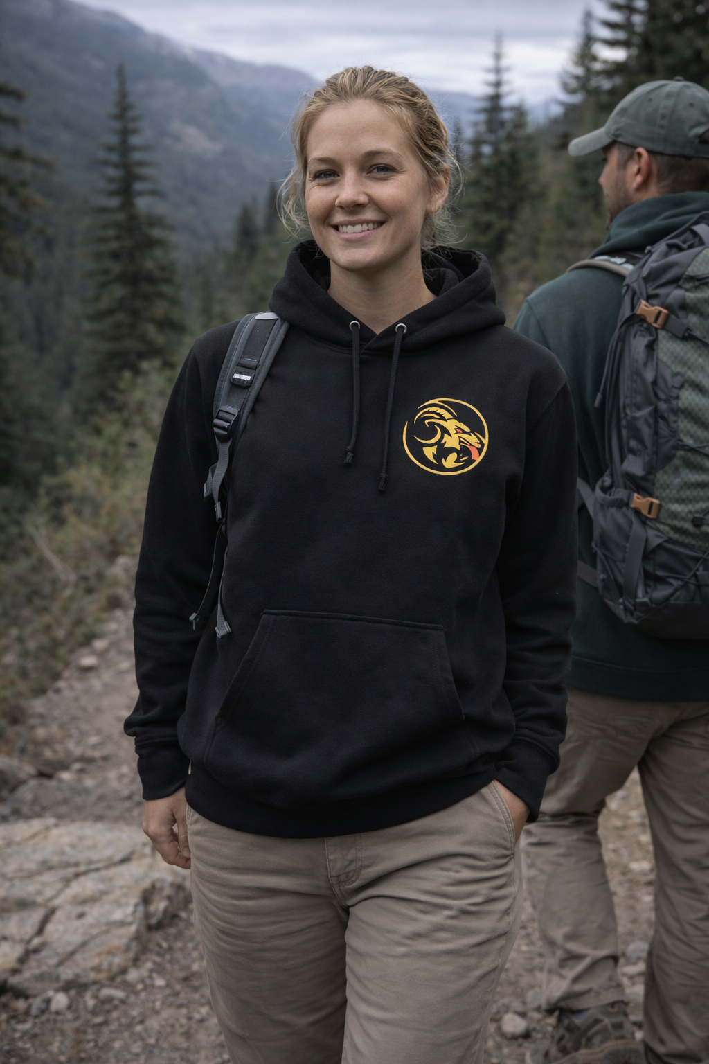 Person wearing a black hoodie with Naughty goat logo in a mountainous outdoor setting