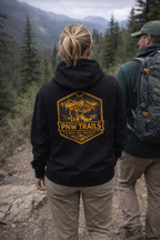 Two people hiking in a mountainous area with one wearing a black hoodie featuring 'PNW Trails' design.