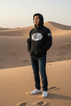 Person wearing a black hoodie with a logo in a desert setting