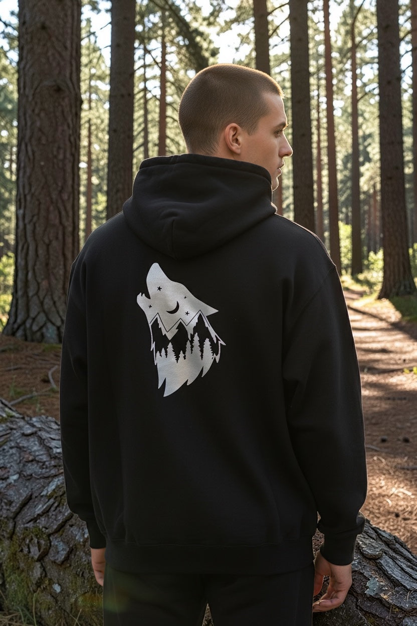 Black hoodie with a white graphic on the back, standing in a forest.